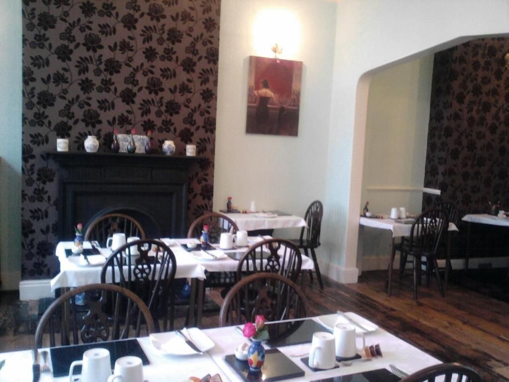 A dining area with tables set for service, a fireplace, and a wall-mounted picture.