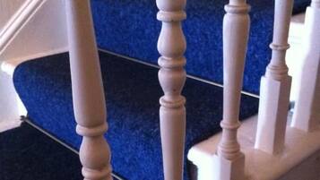 Een trap met witte balustrades en tredes bekleed met blauw tapijt.