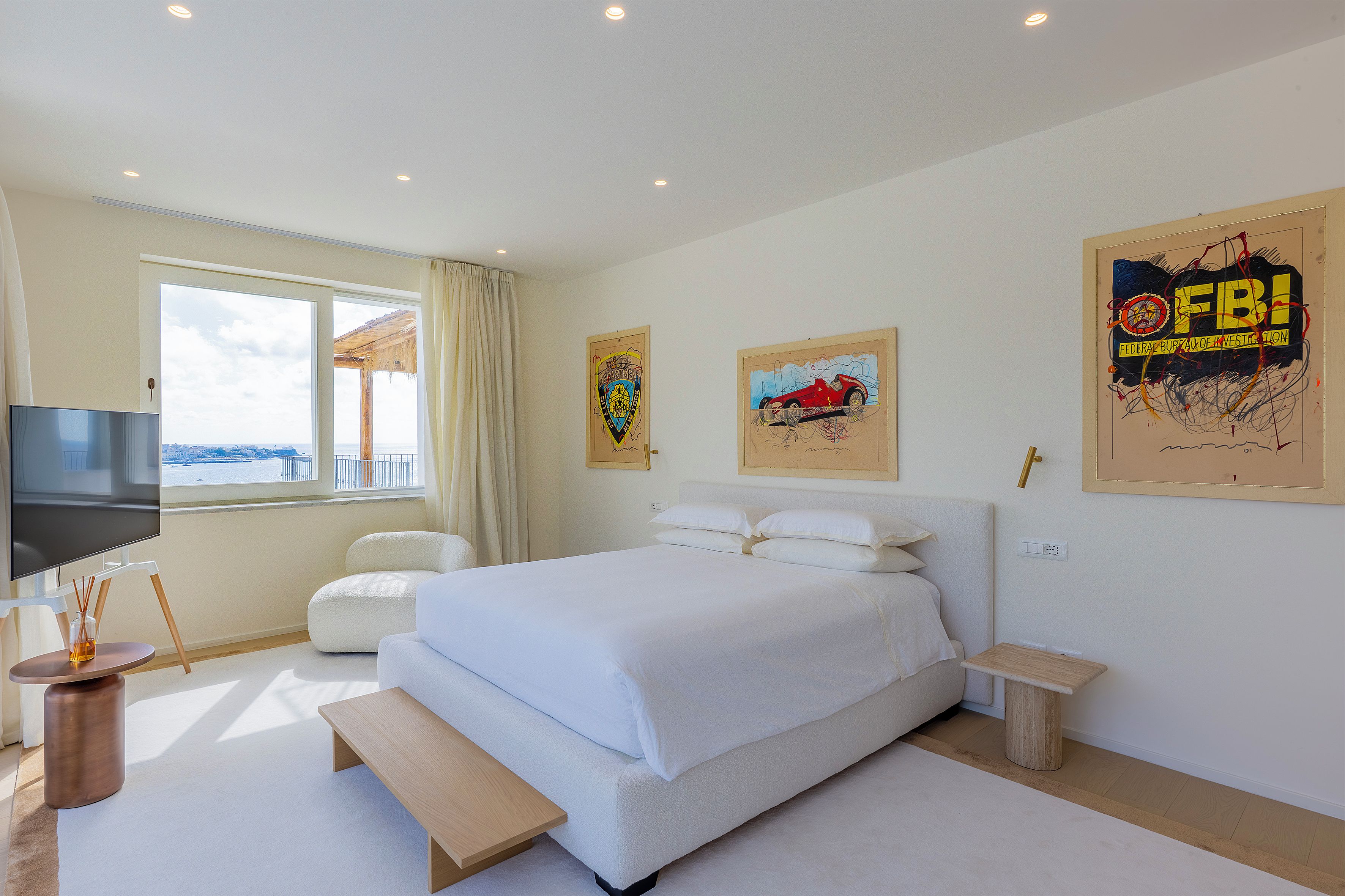 Ein Hotelzimmer mit einem großen Bett, einem Fernseher, einem Fenster mit Blick und Kunstwerken an den Wänden.