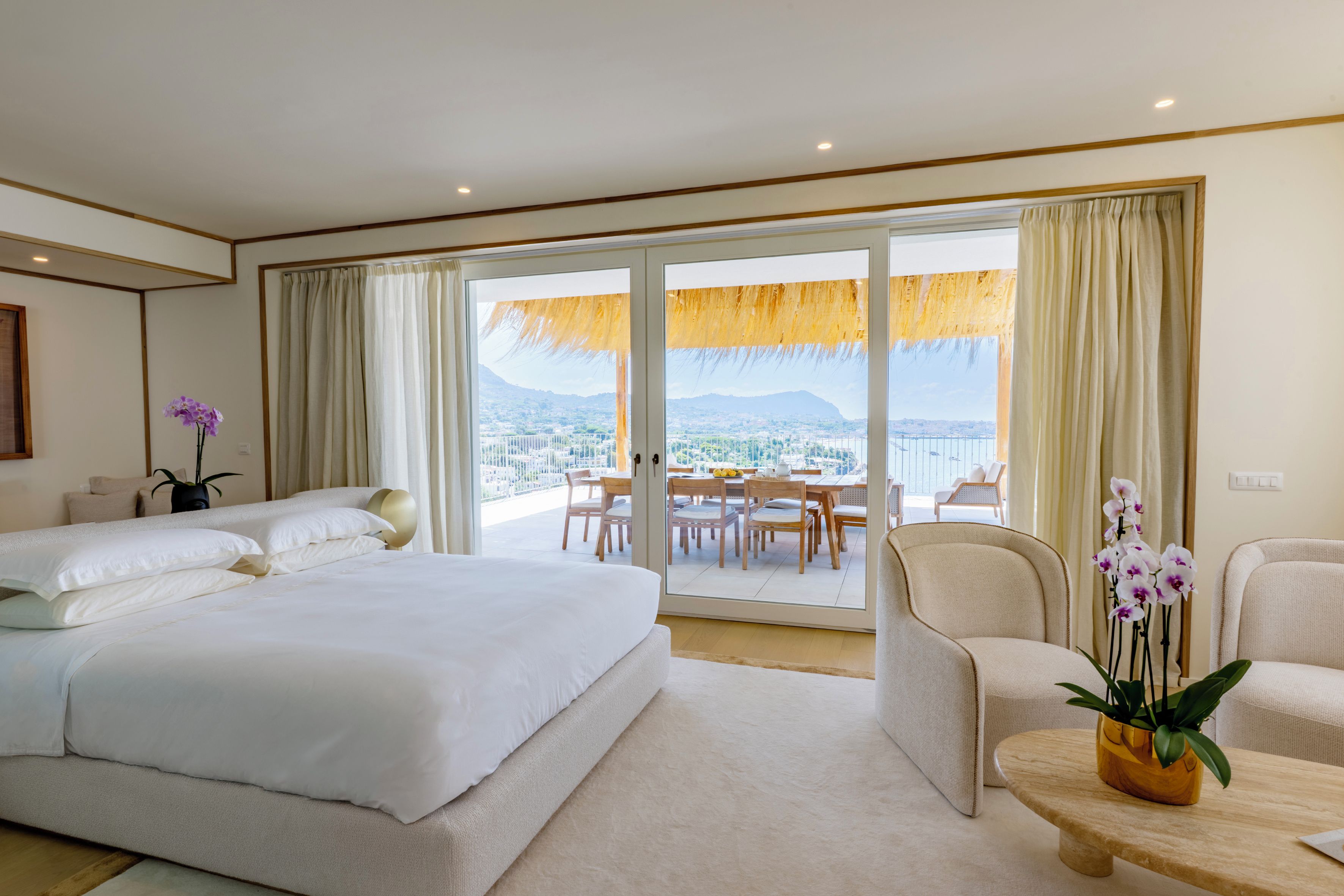 Une chambre d’hôtel avec un grand lit, un coin salon avec une table et une vue sur le paysage urbain par la fenêtre.