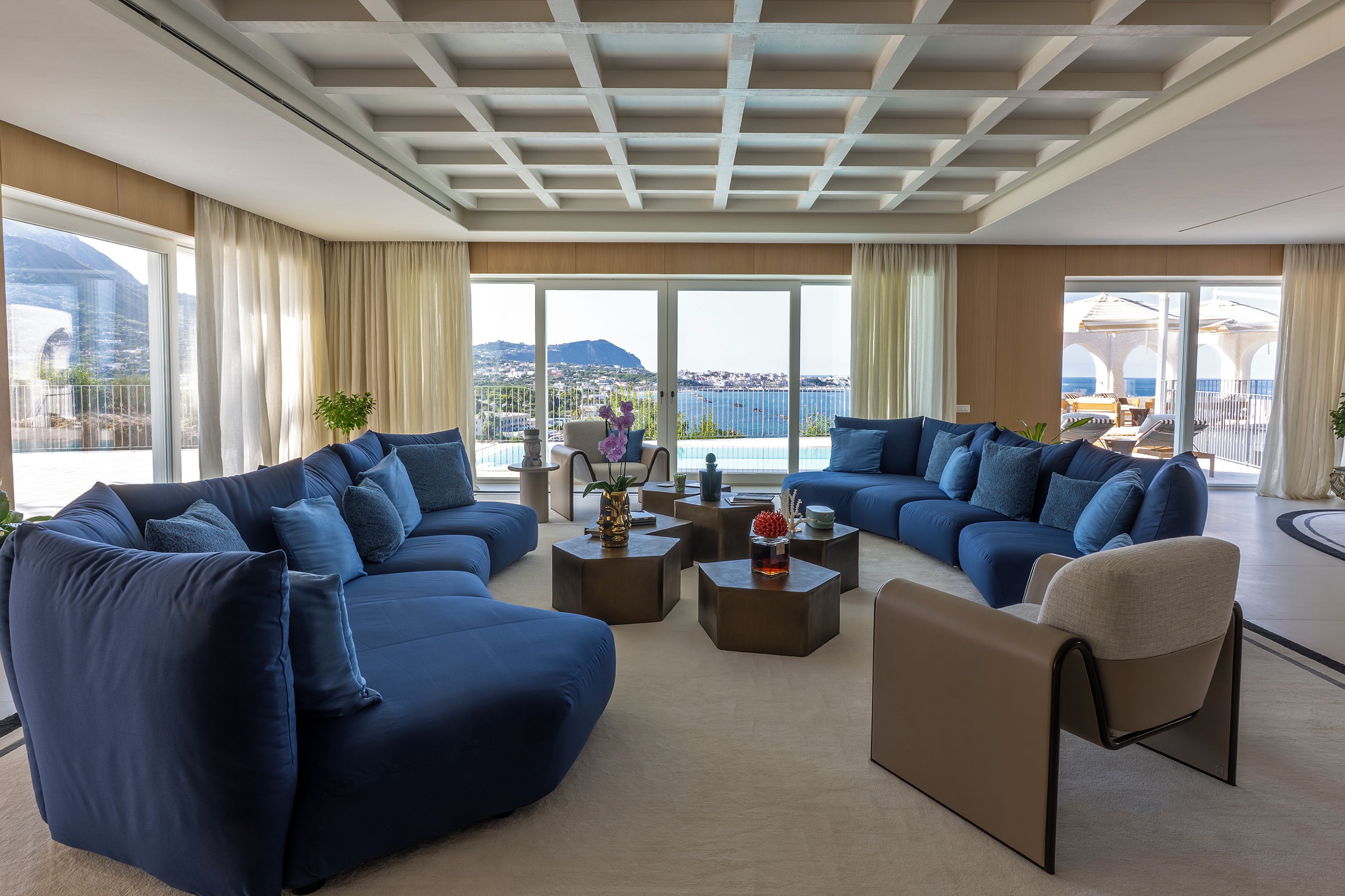 Una sala de estar moderna con un amplio sofá modular, una mesa de centro y vista al mar.