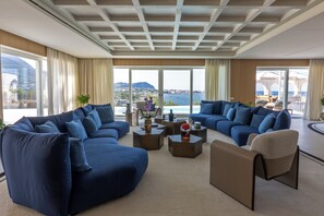 A modern living room with a large sectional sofa, a coffee table, and a view of the sea. - Villa Fenix by My Villa Collection (Forio d'Ischia)