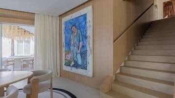 Un interior moderno con una escalera, una zona de comedor y un cuadro grande en la pared.