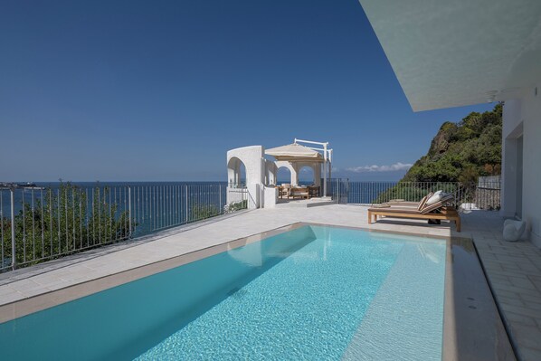 A clear blue swimming pool with a view of the sea, a white gazebo, and lounge chairs. - Villa Fenix by My Villa Collection (Forio d'Ischia)