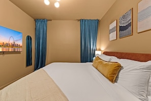 Habitación de hotel con cama, cortinas, un cuadro de paisaje urbano y obras de arte en las paredes.