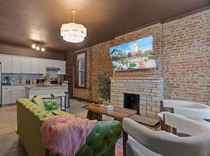 Una sala de estar moderna con chimenea, televisor montado en una pared de ladrillo y un sofá verde.