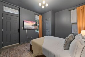A bedroom with a bed, a television mounted on the wall, and a window with curtains.