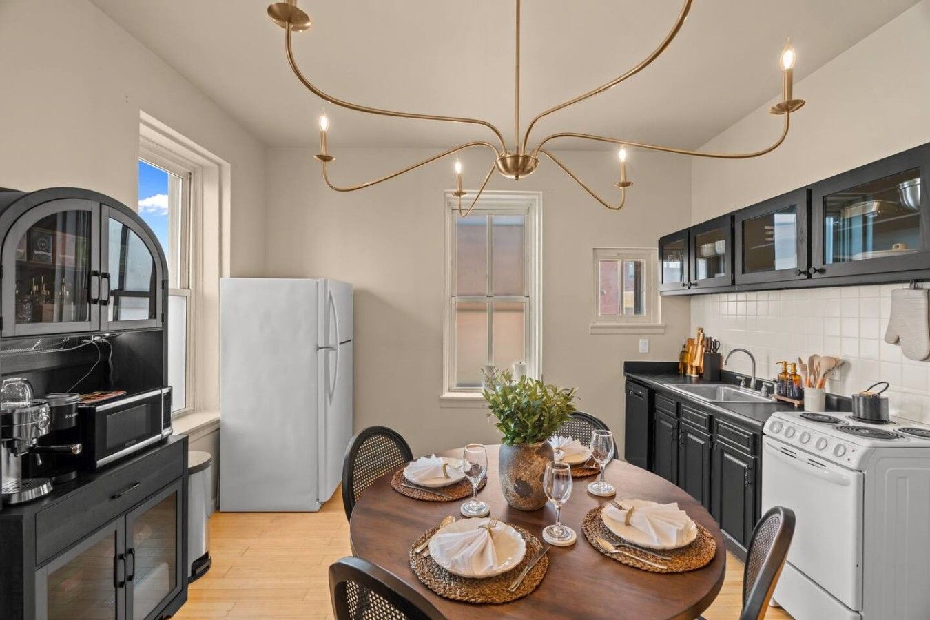 Una cocina moderna con una mesa de comedor para cuatro personas, un refrigerador, una estufa y una cafetera.
