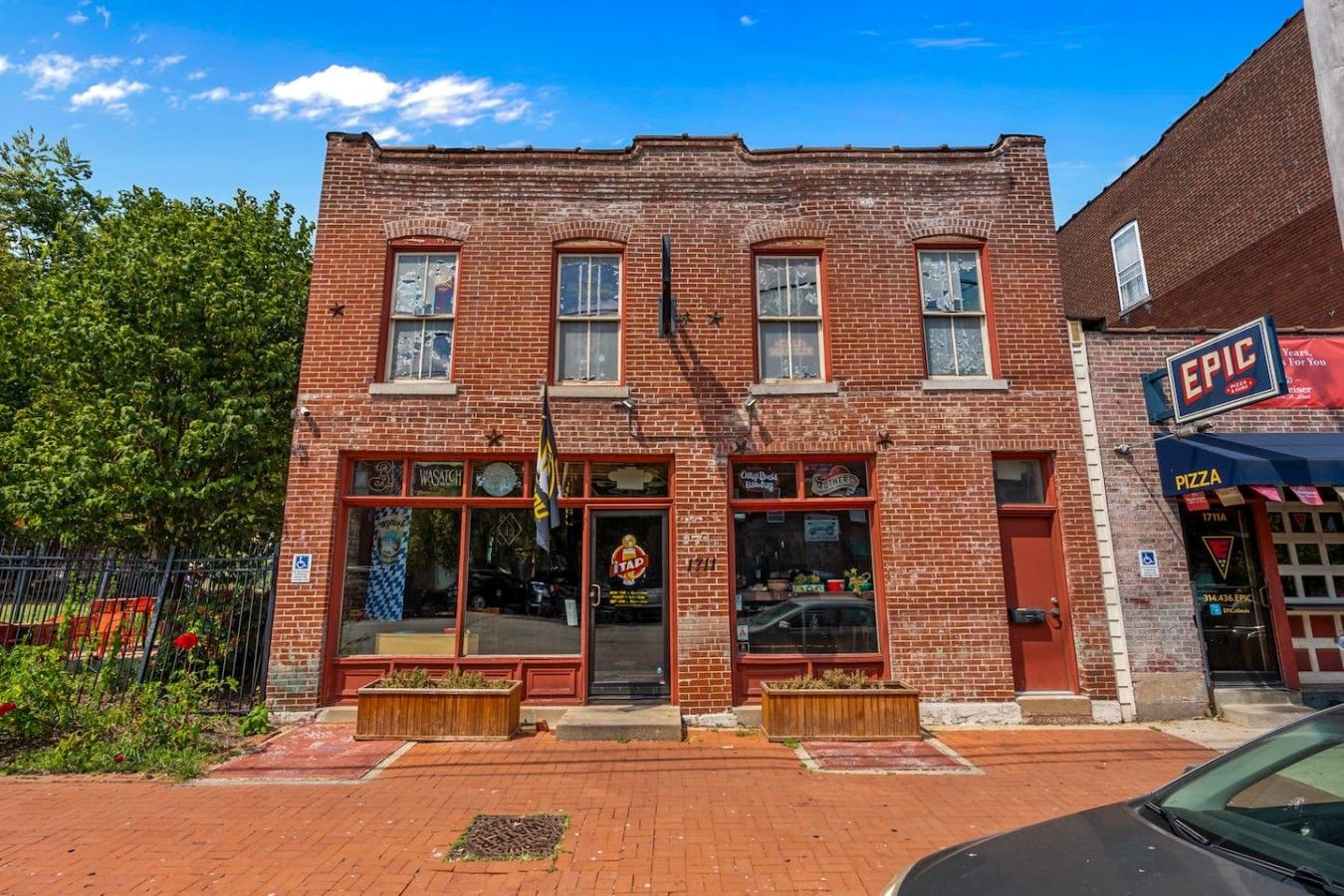 A brick building with a storefront featuring a pizza sign and a flag.