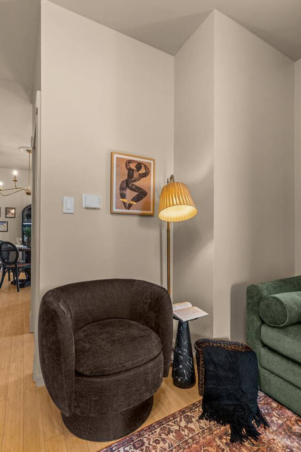 Una sala de estar moderna con un sillón marrón oscuro, un sofá verde, una lámpara de pie y una alfombra estampada.