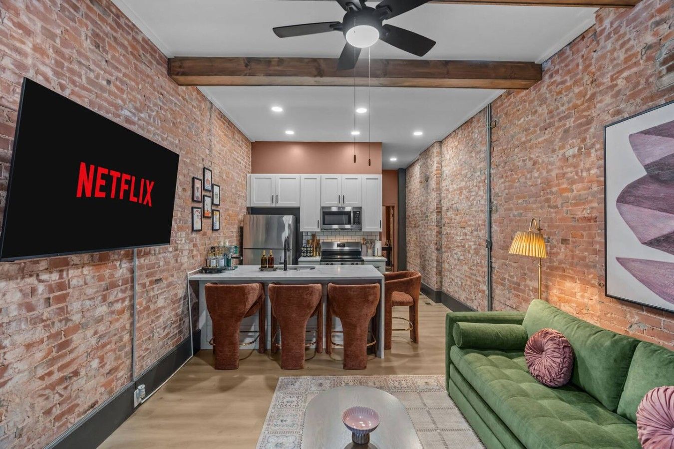 Una cocina moderna con armarios blancos, un refrigerador de acero inoxidable y una zona de bar con taburetes.