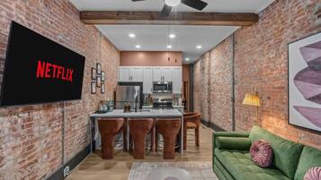 Una cocina moderna con armarios blancos, un refrigerador de acero inoxidable y una zona de bar con taburetes.