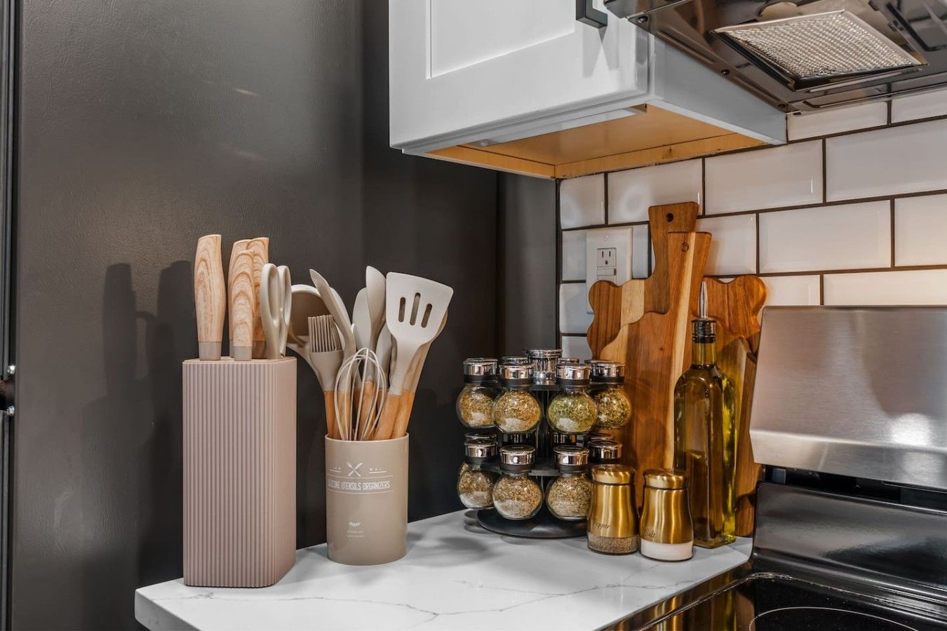 Una encimera de cocina con utensilios, frascos de especias y una botella.