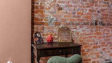 A room with a brick wall, a desk with a chair, and a decorative mirror.