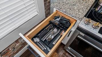 A kitchen with a drawer containing utensils and a stove.