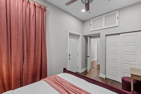 Una camera da letto con un letto, una ventola a soffitto e vista su un corridoio con porte.
