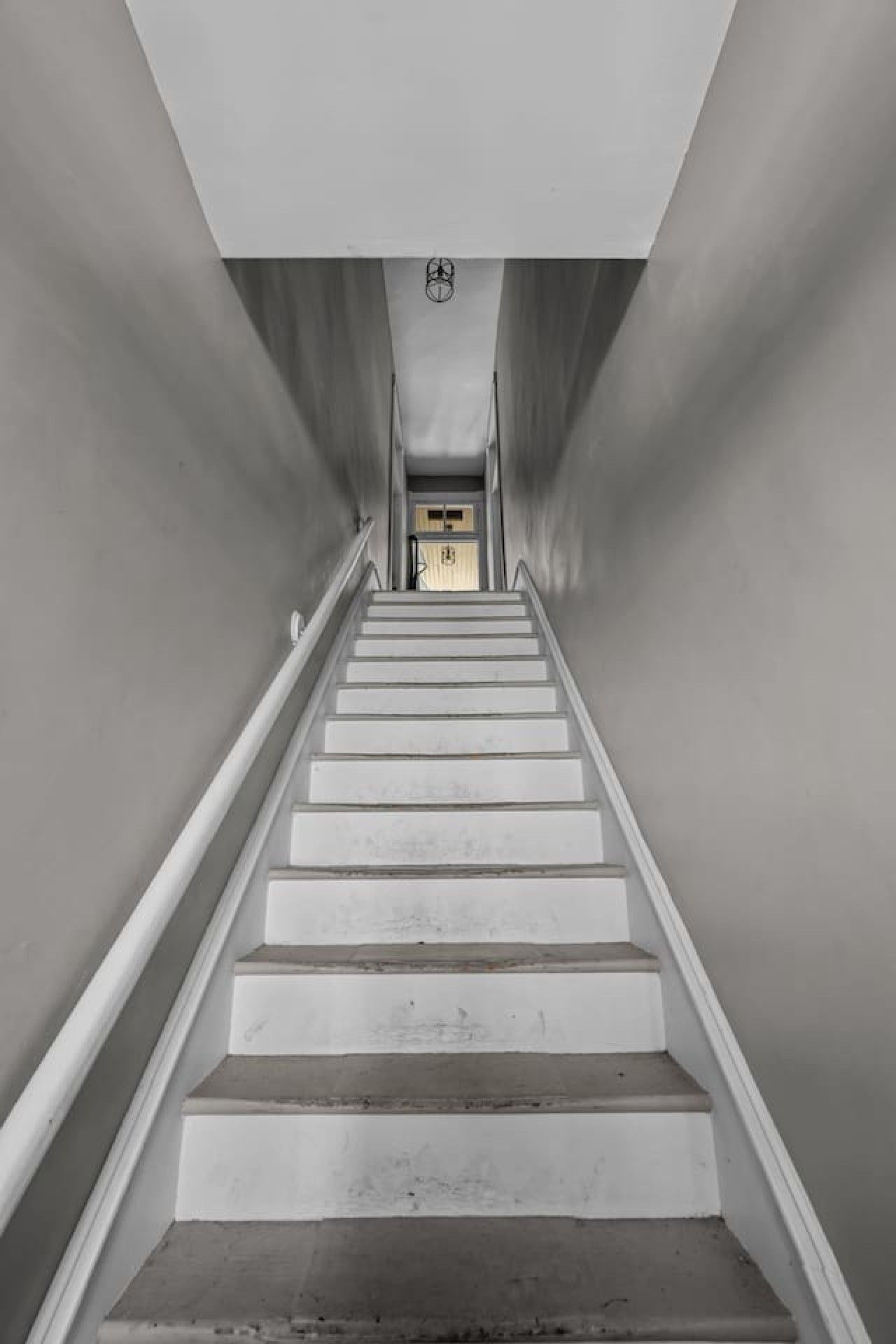 Una scala con corrimano che porta a una porta in cima.