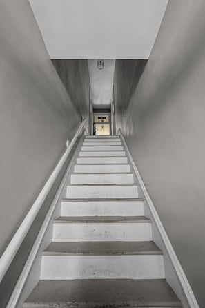 Una scala con corrimano che porta a una porta in cima.