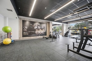 A gym with exercise equipment, a large poster, and a view of the outdoors. - Upscale 1BR | Gym + Coworking Area + Balcony (Kitchener)