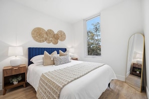 A bedroom with a bed, bedside tables, a window, and a mirror. - Upscale 1BR | Gym + Coworking Area + Balcony (Kitchener)