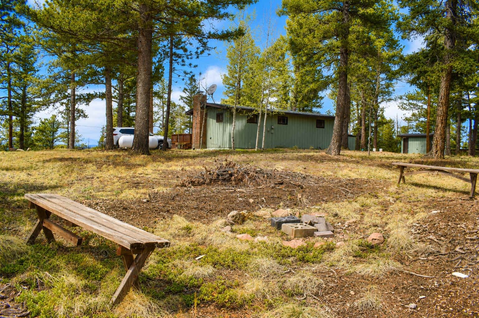 A campsite with a wooden bench, a small shed, and a picnic table.