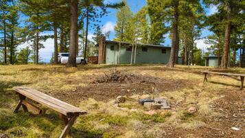 A campsite with a wooden bench, a small shed, and a picnic table.