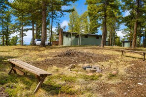 En campingplats med en träbänk, ett litet förråd och ett picknickbord.