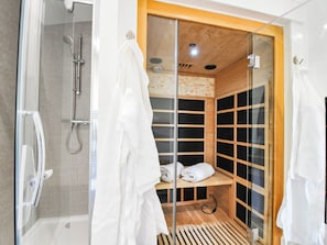 Ein modernes Badezimmer mit einer gläsernen Dusche, einer Holzsauna und einem weißen Handtuchhalter.