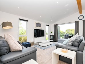 Ein modernes Wohnzimmer mit einer Couch, einem Couchtisch und einem Fernseher auf einem weißen Schrank.