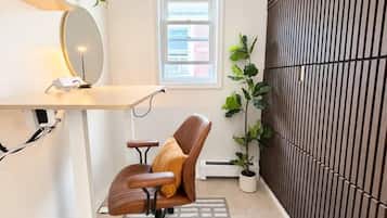 A modern office space with a desk, chair, shelving, and a potted plant.