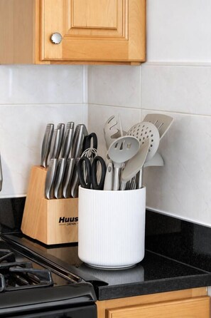 A kitchen with a wooden cabinet, a knife block, and a utensil holder on the counter. - A Rare, Spacious Retreat - Downtown JC, Free Parking, Close to PATH (Jersey City)