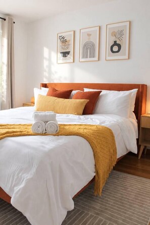 A neatly made bed with white linens, a yellow throw blanket, and rolled towels. - A Rare, Spacious Retreat - Downtown JC, Free Parking, Close to PATH (Jersey City)