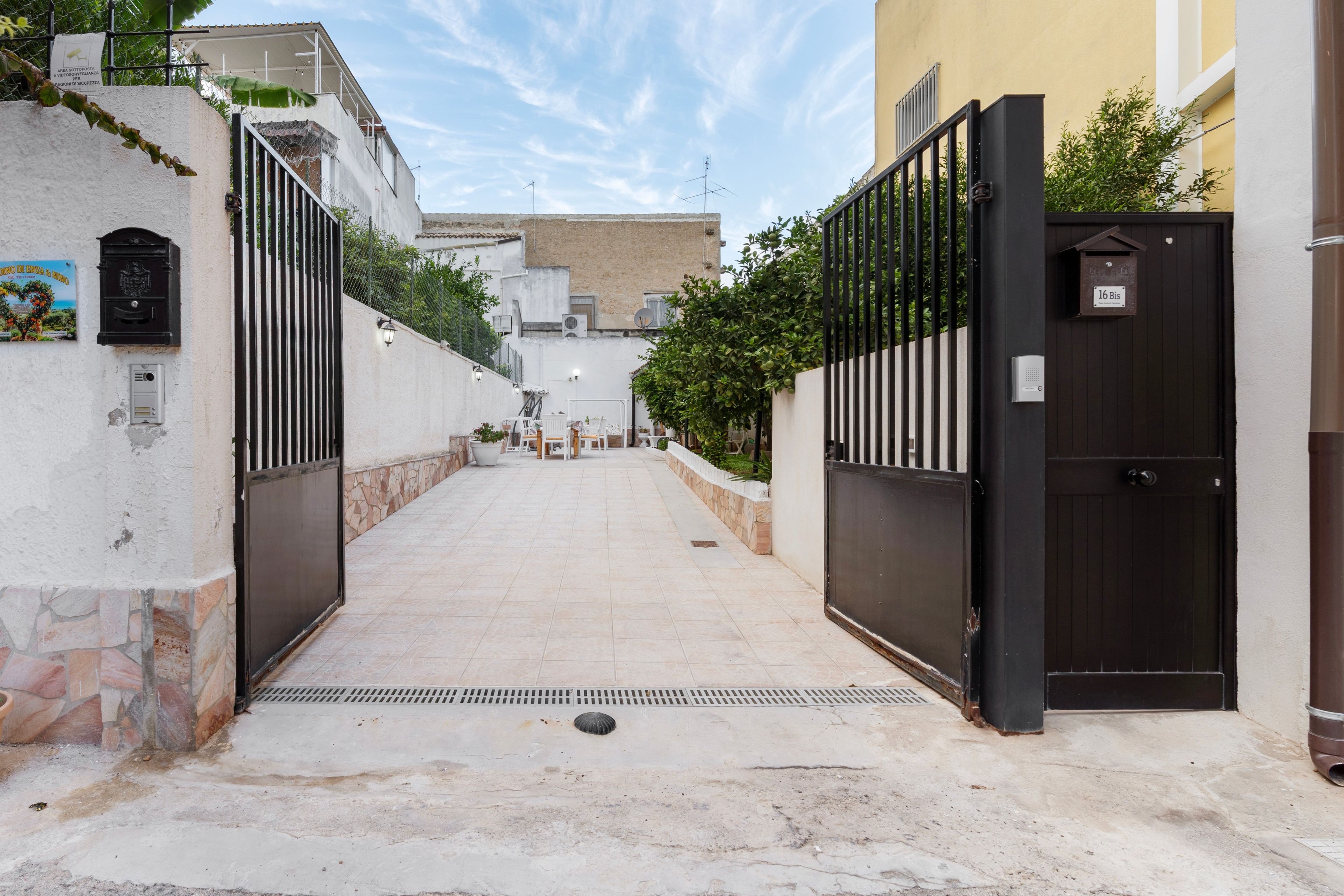 A gated entrance to a property with a tiled pathway leading to a building.