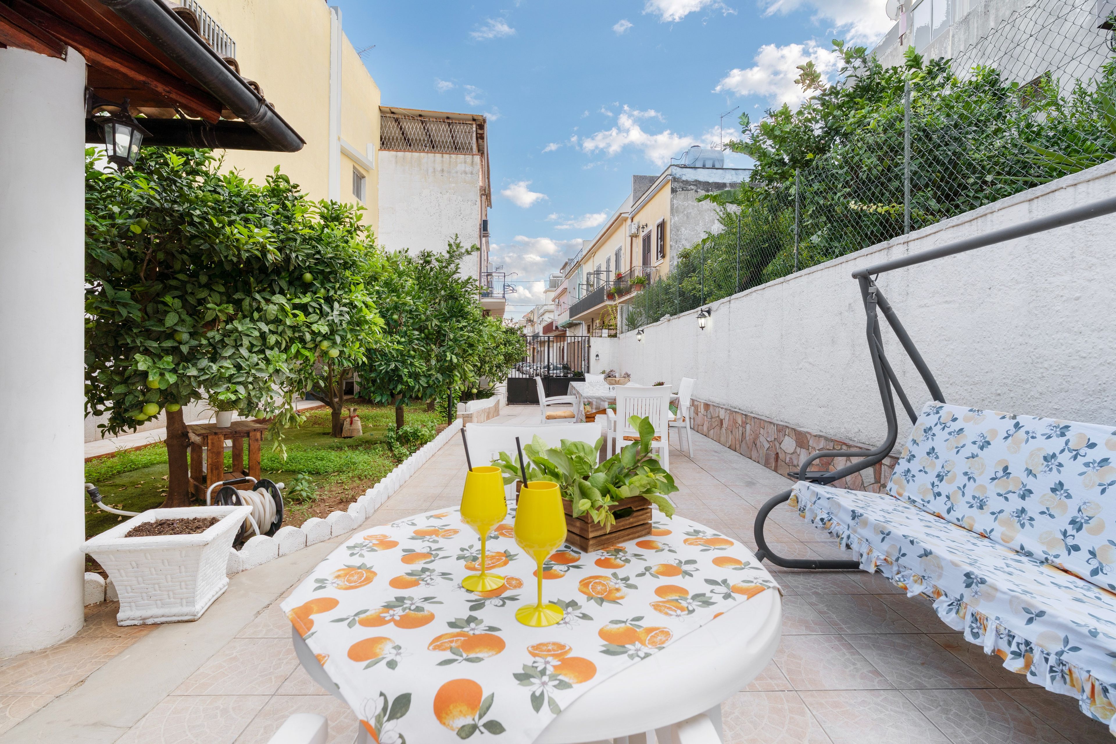 Une terrasse avec une table, deux chaises, un canapé et un pot de fleurs.