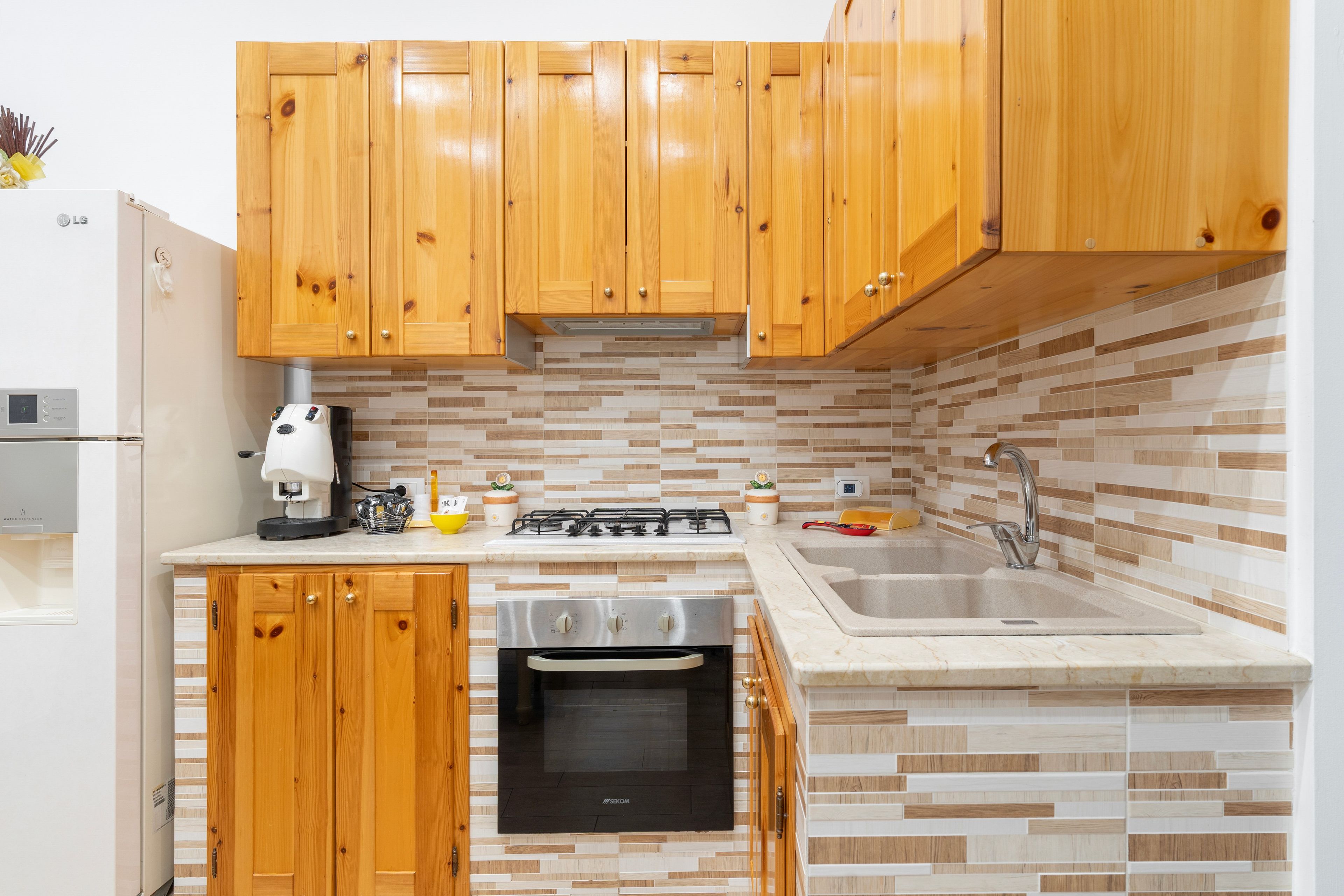 A compact kitchen with wooden cabinets, a built-in oven, a gas stove, and a sink.