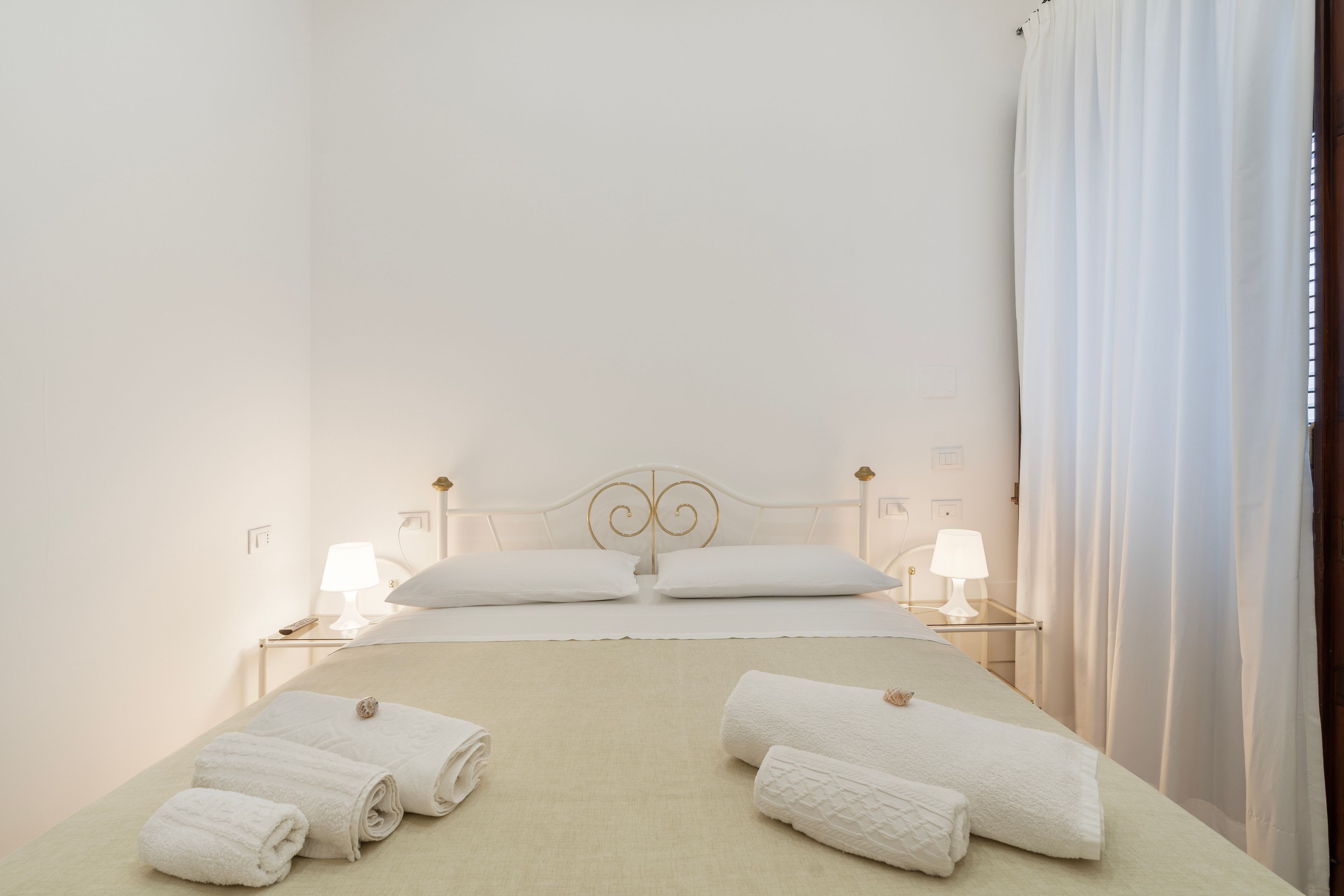 A hotel room with a bed, two bedside tables, two lamps, and towels.