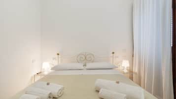 A hotel room with a bed, two bedside tables, two lamps, and towels.