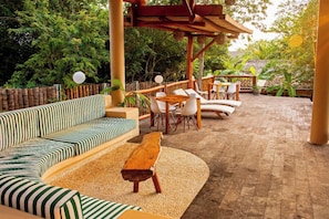 An outdoor seating area with a sofa, chairs, and a wooden table. - La Siesta Troncones    Beautiful Cozy Palapita (Troncones)