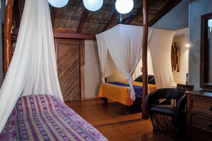 Une chambre avec deux lits, chacun doté d’un baldaquin, une chaise, une table et un plafond en bois.