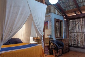 A room with a bed, a chair, a desk, and a window with bamboo blinds. - La Siesta Troncones    Beautiful Cozy Palapita (Troncones)