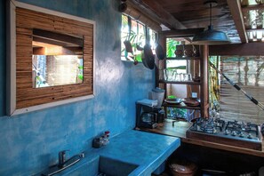 A kitchen with a wooden countertop, a sink, a stove, and hanging pots. - La Siesta Troncones    Beautiful Cozy Palapita (Troncones)