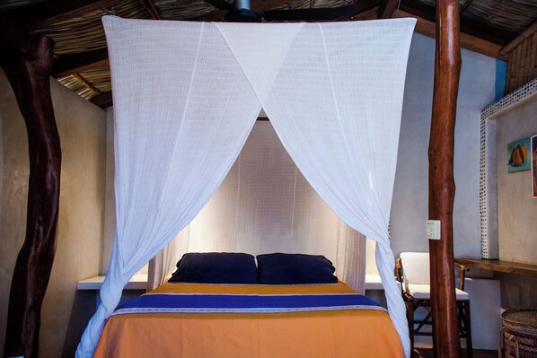 A bed with a canopy, a wooden chair, and a wall-mounted light switch. - La Siesta Troncones | 4 Villas & Pool (Troncones)