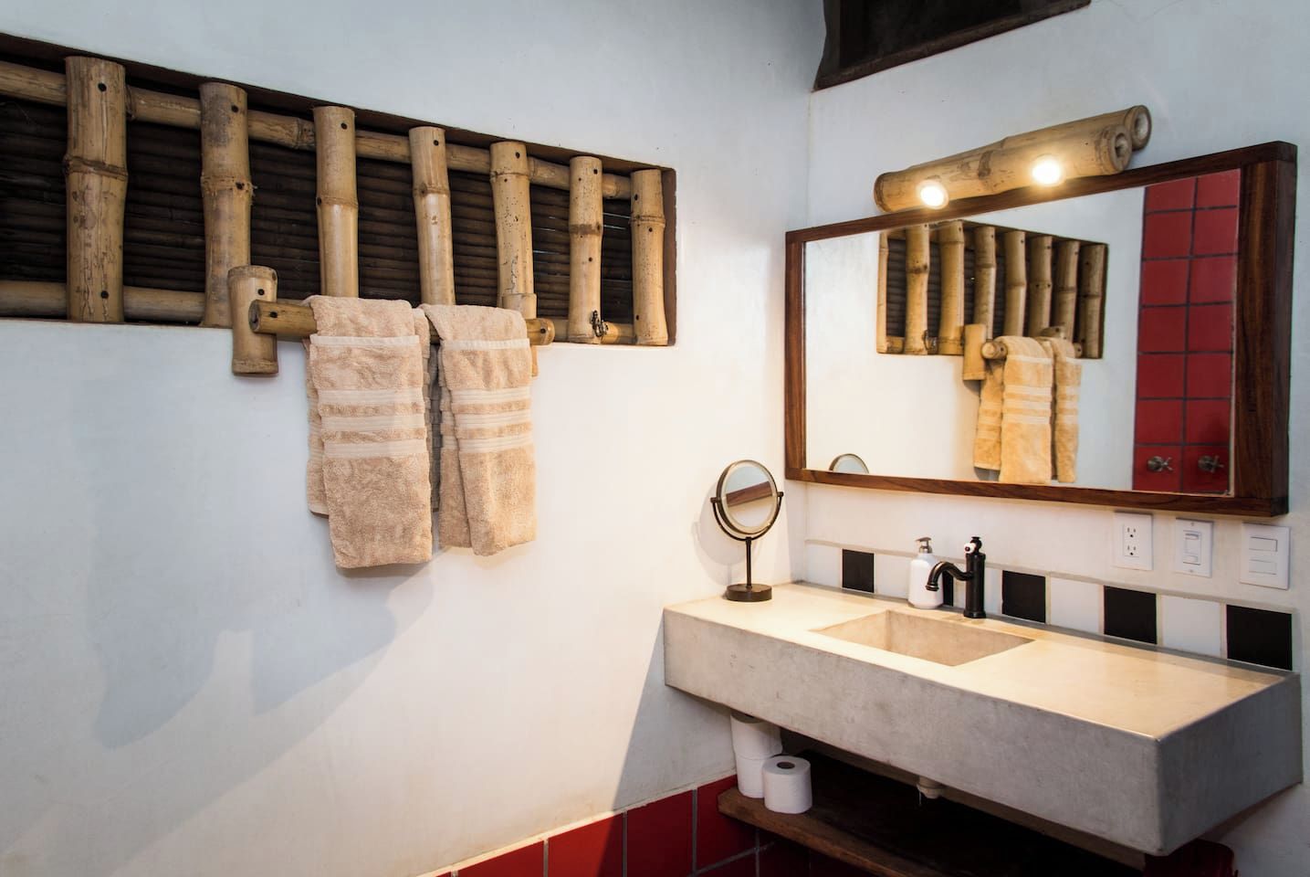 A bathroom with a wooden towel rack, a mirror, and a sink.