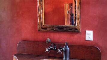 Un baño con tocador de madera, un espejo y un aplique en la pared.