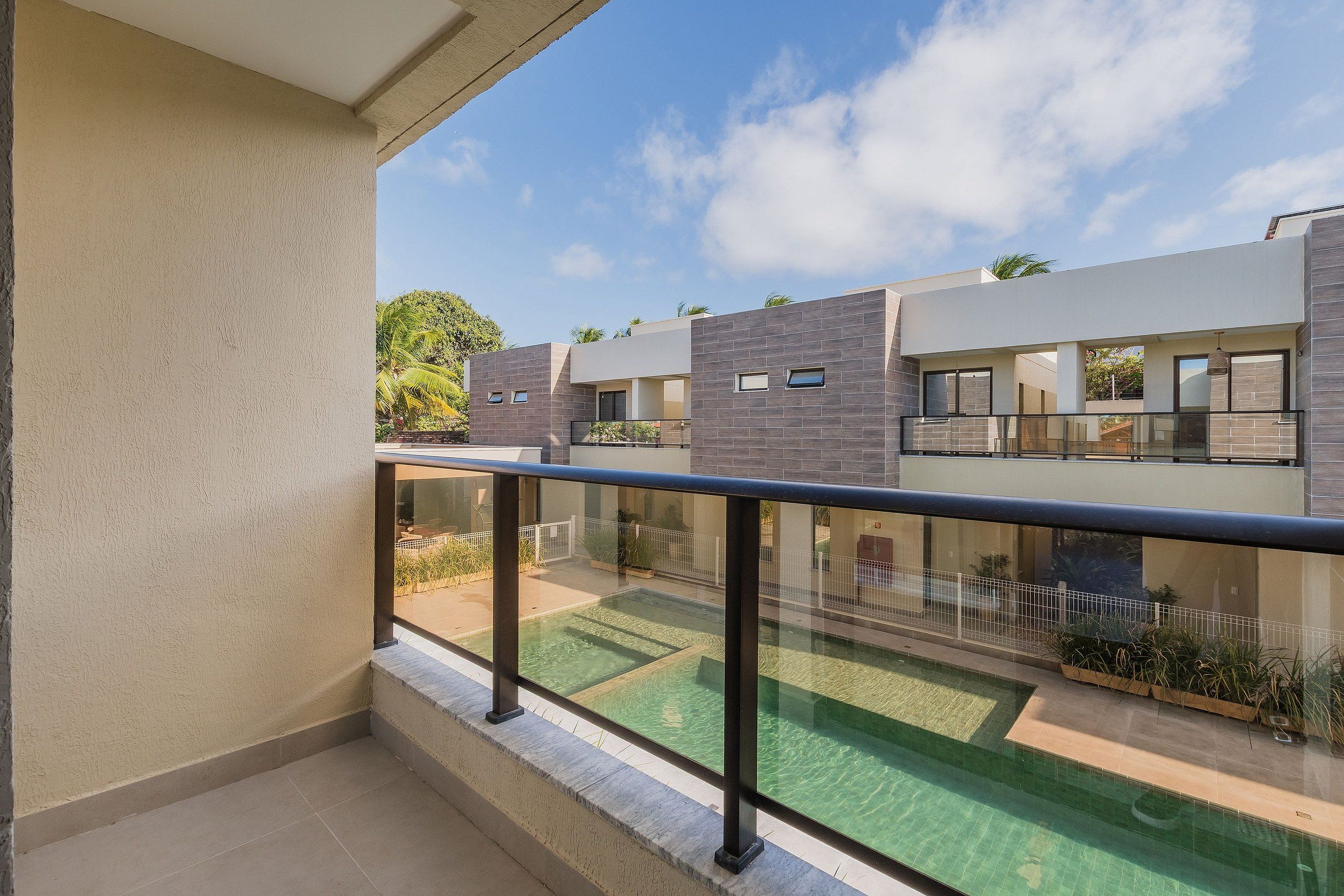 A modern building with a flat roof, large windows, and a balcony with a glass railing.