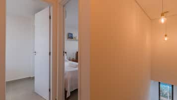 Ein Hotelzimmer mit Bett, Nachttisch, Lampe und einem Fenster mit Blick auf Grünflächen.