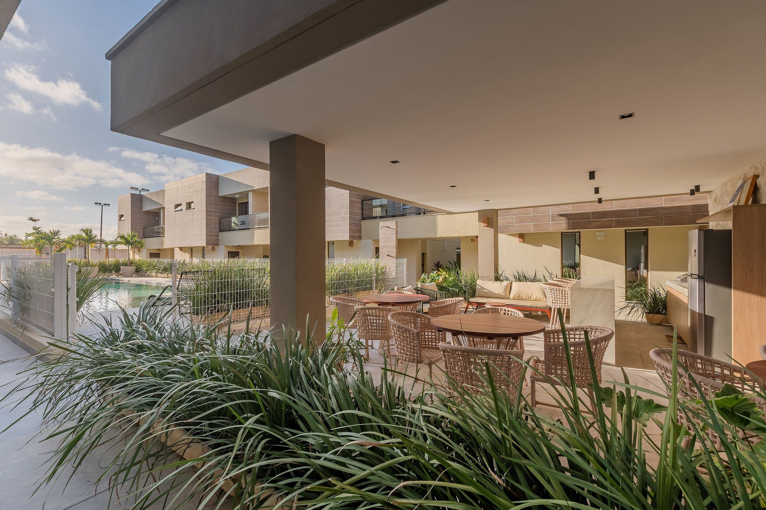 Un espace extérieur moderne, aménagé en terrasse, avec une piscine, des fauteuils et des plantes en pot.