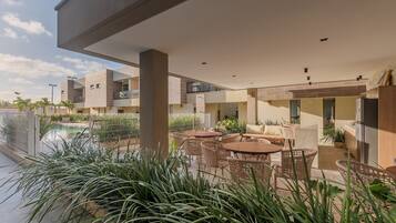 Un espace extérieur moderne, aménagé en terrasse, avec une piscine, des fauteuils et des plantes en pot.