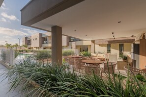 A modern outdoor patio area with a pool, lounge seating, and potted plants.
