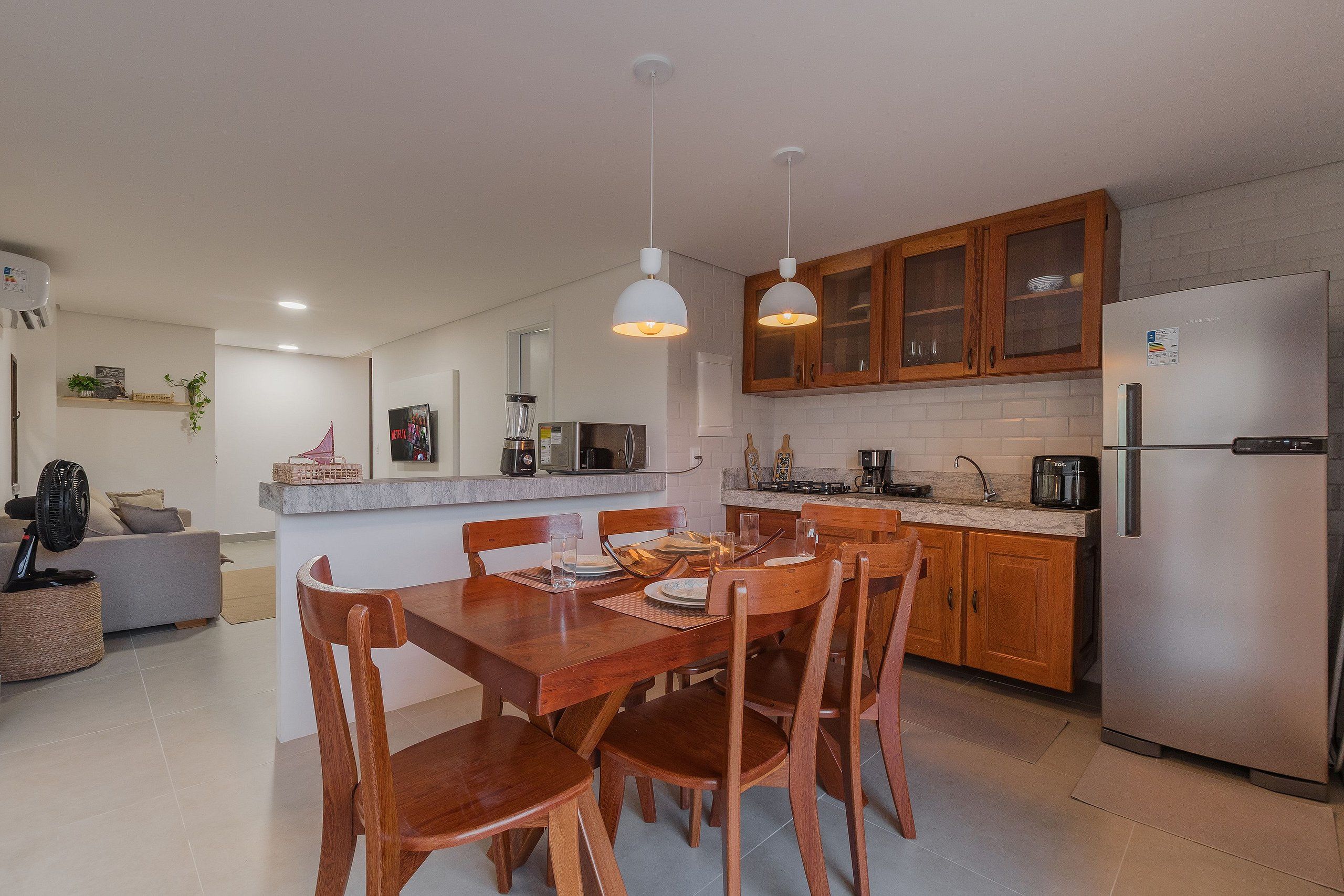 A modern kitchen with wooden cabinets, a built-in microwave, and a stainless steel refrigerator.